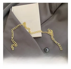 Close-up of golden metal chain strap and white pleated cloud bag detail on a blazer