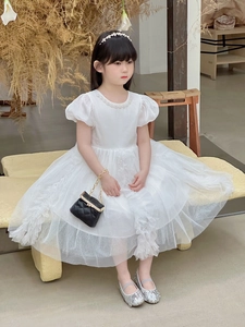 Close-up of white tulle girls dress with pearl collar and layered ruffle skirt details