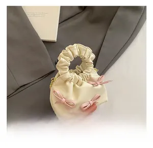Detail of cream pleated mini handbag with pink bows and elegant cloud style handle