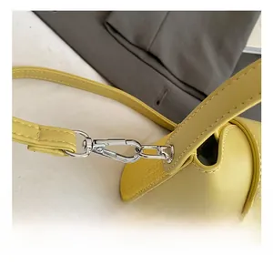 Detailansicht der gelben Ledertasche mit silbernem Metallhaken und präzisen Nähten