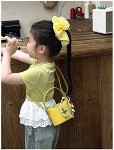 Detail der gelben Mini-Handtasche mit Perlenanhänger, Puppe und Metall-Drehverschluss