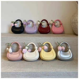 Multi-colored mini crescent bags with tulip pendants displayed on stone steps