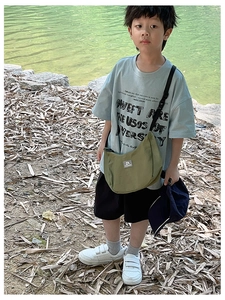 Detail of olive green nylon crossbody bag on a child's casual outdoor sports outfit
