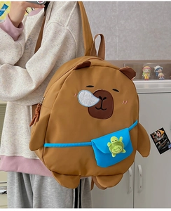 Detail of Capybara backpack for kids featuring blue front pocket and green turtle charm
