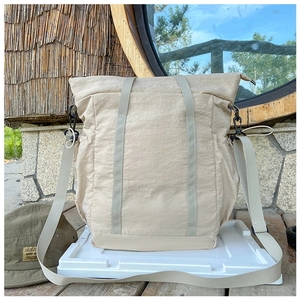 Outdoor shot of a beige water-resistant nylon kids travel bag with drawstring and straps