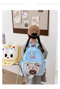 Rear view of a child wearing a light blue cartoon cat backpack with purple straps