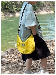 Detail of bright yellow crescent crossbody bag with adjustable strap and brand label