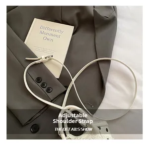 Détail de la bandoulière réglable en cuir blanc avec boucle argentée sur sac à pois