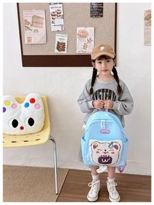 Light blue kids backpack with 3D teddy bear design worn by a child in home setting