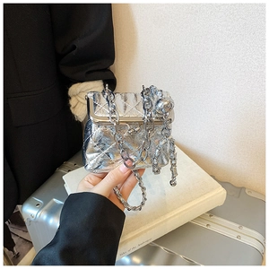 Detailed view of silver quilted mini bag with metallic chain and gold ball charm detail