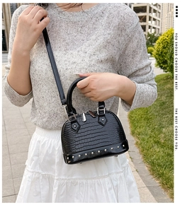 Detail of black faux crocodile shell bag with silver stud rivets on the bottom