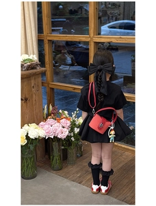Detail der roten gewebten Mini-Tasche mit Puppenanhänger und Gurt an einem Kindermodel