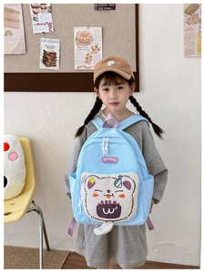 Close-up of light blue kids backpack featuring cute bear pockets and purple handle
