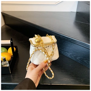Detail of white quilted crossbody bag with golden chain strap and ball ornament