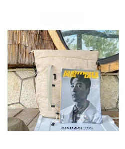 Detail of canvas travel bag with grey webbing handles and drawstring on a stone background