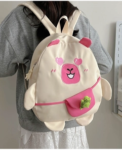 Detail of cute beige cartoon backpack with pink heart eyes and green turtle keychain charm