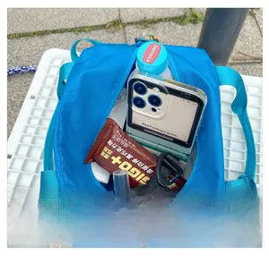 Top view of spacious blue nylon travel bag interior filled with water bottle and phone