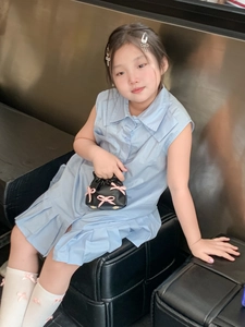 Close-up of a sweet girl outfit featuring a blue pleated dress and a black bow handbag