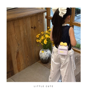 Sac bandoulière violet pour fille avec nœud jaune et chaîne porté par un enfant
