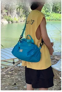 Detail view of a blue nylon kids travel shoulder bag with teal straps in an outdoor setting