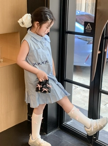 Side view of child model wearing blue sleeveless dress and mini cloud handbag