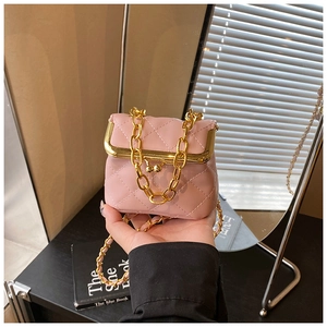 Pink quilted crossbody bag with gold metal frame and ball clasp shown in hand