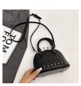 Detail of black shell crossbody bag with silver bottom rivets and crocodile pattern texture