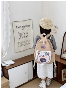 Close-up of cute cartoon cat pattern on a beige children's backpack worn by a child
