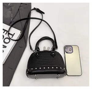 Close-up of mini crocodile pattern shell bag with silver rivets and metal feet detail