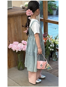 Detail der rosa Mädchentasche mit Bärenanhänger und grünem Denim-Kleidungsset für Kinder