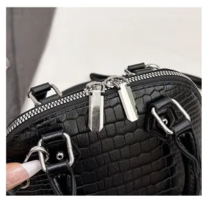 Detail of a black croc-effect shell bag showing smooth double silver metal zippers