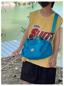 Blue kids travel bag featuring a durable nylon fabric and adjustable green shoulder strap