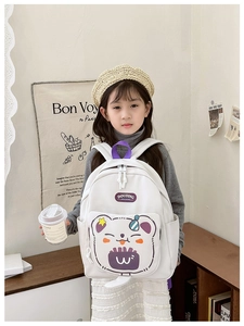 Close-up of white children's backpack featuring cute purple cartoon bear and side pockets