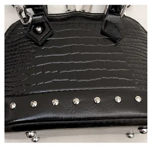Macro shot of black crocodile-embossed leather handbag with silver stud details