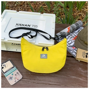 Outdoor shot of bright yellow nylon crescent crossbody bag on a wooden bench