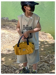 Detailed view of yellow nylon kids travel bag with black handles in outdoor setting