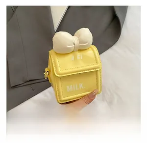Détail du mini sac bandoulière jaune avec un grand nœud blanc et des lettres