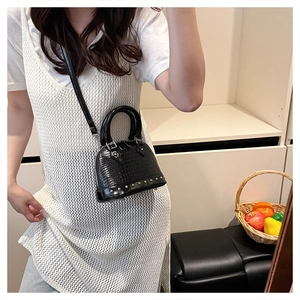 Detail of black crocodile pattern shell bag with silver rivets and sleek dual handles
