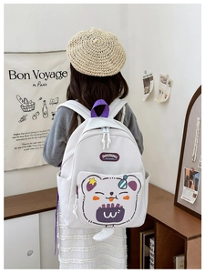 Detail view of a white canvas school bag featuring cute cartoon bear print and purple straps
