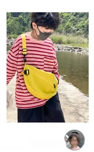 Gros plan d'un sac bandoulière jaune en nylon pour enfant avec sangle réglable en extérieur