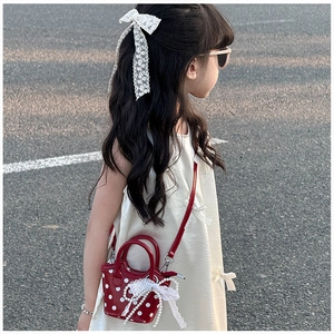 Détail du sac rouge à pois pour fille avec nœud en dentelle et pendentif perle
