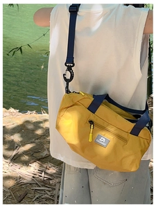 Outdoor shot of a kids yellow nylon crossbody bag with blue straps and TOCHASO logo
