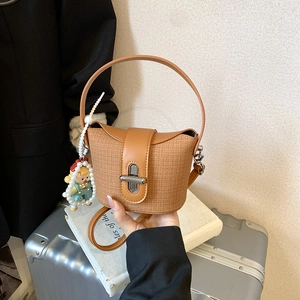 Detail der braunen gewebten Tasche mit Lederstiching und einem süßen Perlen-Anhänger