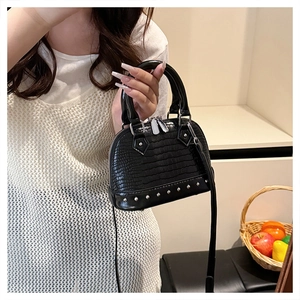 Detailed close-up of black crocodile pattern leather shell bag with silver stud rivets