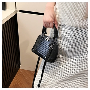 Macro view of black crocodile pattern mini shell bag with silver stud details on base