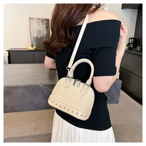 Detail of cream beige mini shell bag with croc-embossed texture and silver rivets