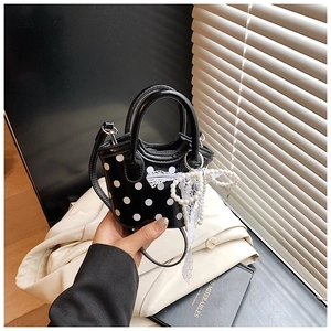 Détail du mini sac à pois noirs avec charm décoratif en perles et nœud en dentelle