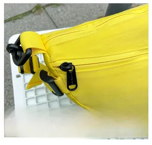 Détail de la fermeture éclair noire et de la boucle sur le sac bandoulière jaune pour enfant