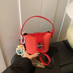 Detail der roten Mini-Beuteltasche mit Webstruktur, Metallschloss und Puppenanhänger