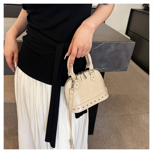 Close-up of creamy white crocodile pattern mini shell bag with silver rivet details